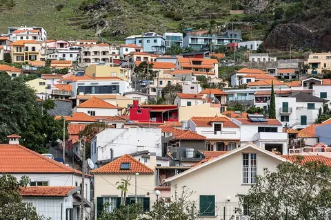 Tiled roofs climb Machico’s hillside, showing the town’s slopes beyond a walk through the centre.